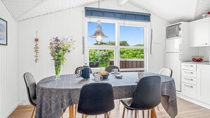 Ein Essbereich mit einem Tisch für vier Personen, einer Blumenvase und Blick auf Grün.
