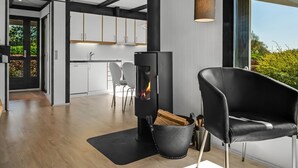 A modern interior with a wood-burning stove, a dining area, and a kitchen with white cabinets. - "Sigbrith" - 350m to the fjord by Interhome (Tarm)