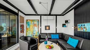 A modern living room with a black leather sofa, a round coffee table with fruit, and a large abstract painting on the wall. - "Sigbrith" - 350m to the fjord by Interhome (Tarm)