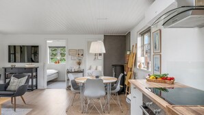 Eine moderne Küche mit Einbauofen, einem Essbereich mit rundem Tisch und Stühlen sowie einem großen Fenster für natürliches Licht.