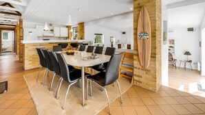 A modern kitchen with white cabinets, a wooden island, and a dining area with a large table and chairs. - "Ewy" - 300m from the sea by Interhome (Ringkøbing)