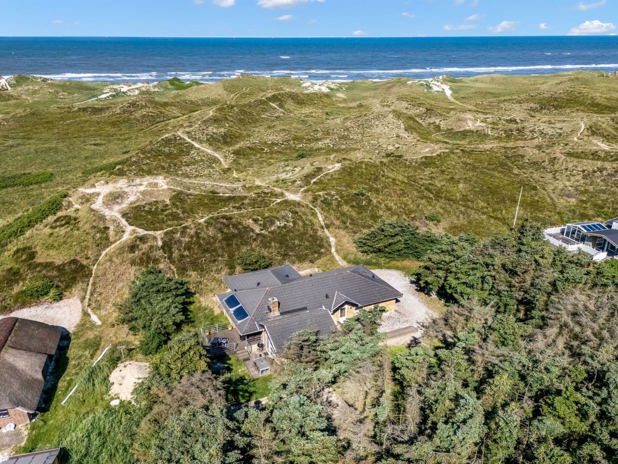 A coastal property with a house featuring a sloped roof, solar panels, and a visible outdoor area.