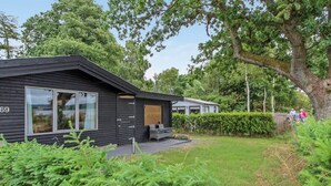 A modern cabin with a large window, a wooden deck, and a view of a lake. - Vacation home "Graa" by Interhome (Skanderborg)