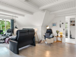 A modern interior with a sloped ceiling, a black leather sofa, a white chair, and a small table with a lamp. - "Lilo" - 1km from the sea by Interhome (Blåvand)
