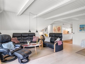 A spacious living area with a high ceiling, black leather sofas, a small round table, and a view into the kitchen. - "Lilo" - 1km from the sea by Interhome (Blåvand)