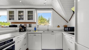 A modern kitchen with white cabinetry, a dishwasher, a microwave, and a coffee maker. - "Tuomi" - 900m from the sea by Interhome (Ringkøbing)