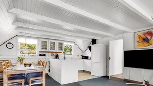 A modern kitchen with white cabinetry, a dining area with wooden chairs, and a large window providing natural light. - "Tuomi" - 900m from the sea by Interhome (Ringkøbing)