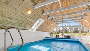An indoor swimming pool with a wooden ceiling and skylights, surrounded by a white wall and a view of the outdoors. - "Tuomi" - 900m from the sea by Interhome (Ringkøbing)