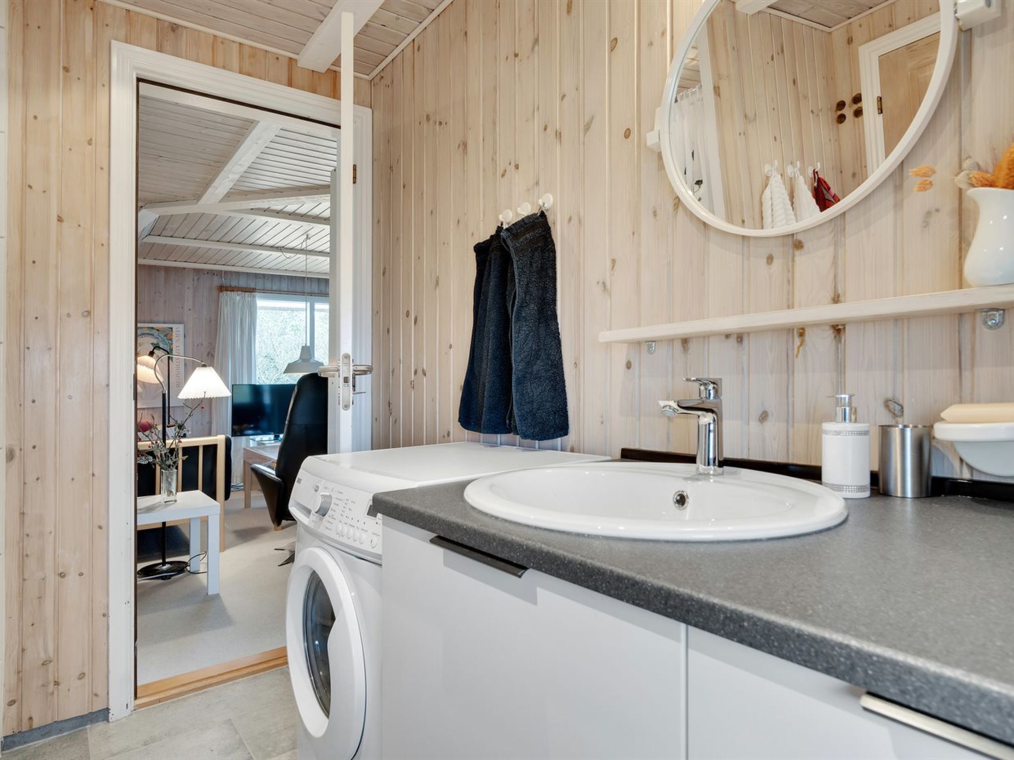 Une salle de bain moderne équipée d’un lave-linge intégré, d’un lavabo et d’un miroir.
