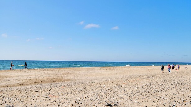 A beach with pebbles and people walking. - "Riborg" -  from the sea by Interhome (Ringkøbing)