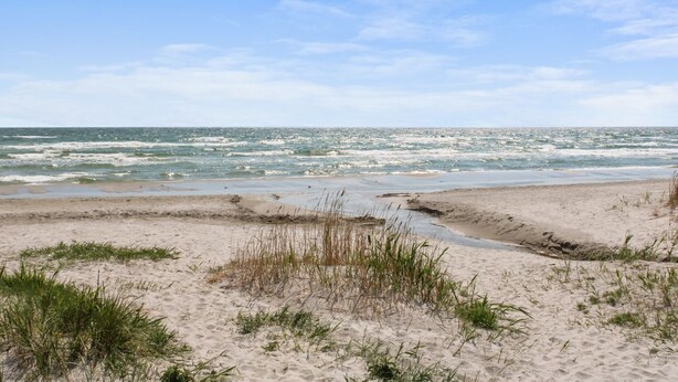 A beach with sand and sparse grass, a clear sky, and the ocean in the background. - "Andria" - 300m from the sea by Interhome (Hals)