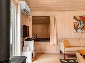 Un intérieur moderne avec un plafond en bois, un canapé, un téléviseur et une fenêtre avec des rideaux.