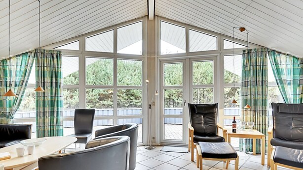 A sunroom with large windows, multiple seating areas, and a tiled floor. - "Guththorm" - 600m from the sea by Interhome (Blåvand)