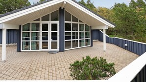 A modern building with a sloped roof, large windows, and a brick-paved deck. - "Guththorm" - 600m from the sea by Interhome (Blåvand)