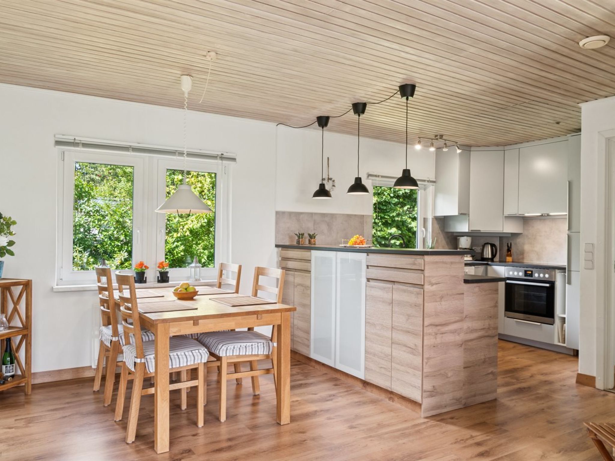 A modern kitchen with wooden cabinets, a central island, and pendant lighting.