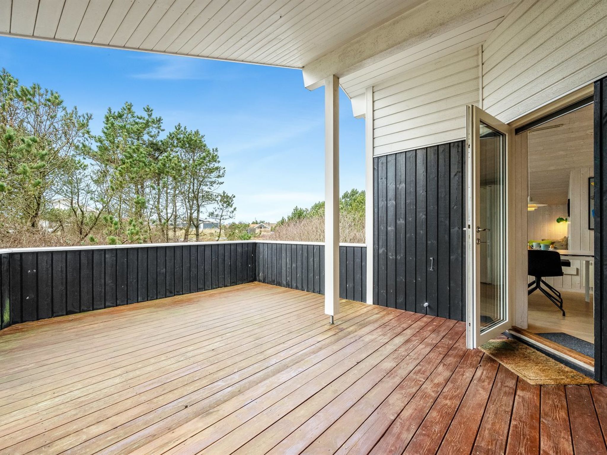 Une terrasse en bois offrant une vue sur les arbres et un bâtiment.
