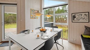Een moderne eetruimte met een witte tafel, zwarte stoelen en een groot raam met uitzicht op groen.