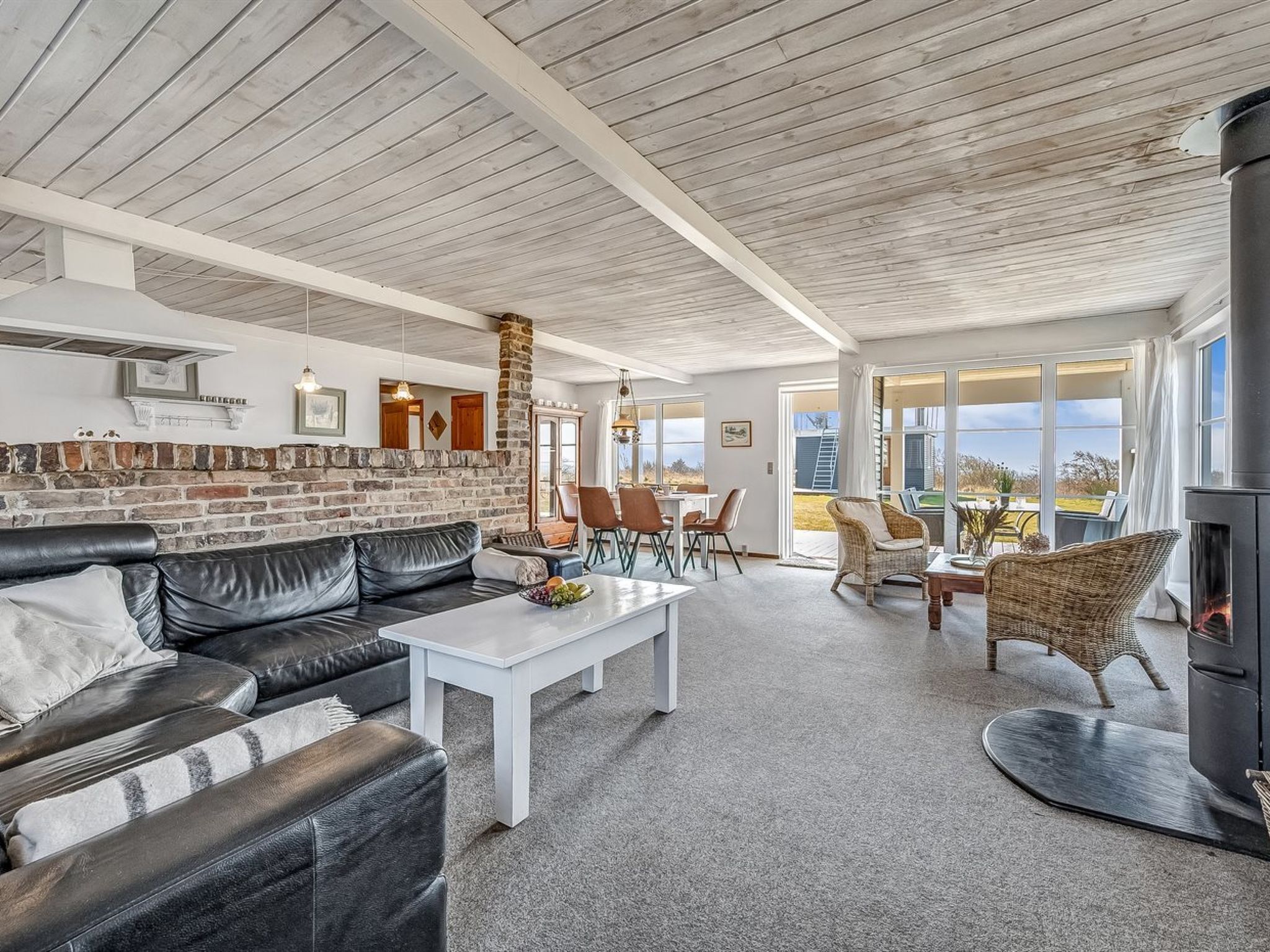 A spacious living area with a brick fireplace, a white coffee table, and a comfortable seating arrangement.