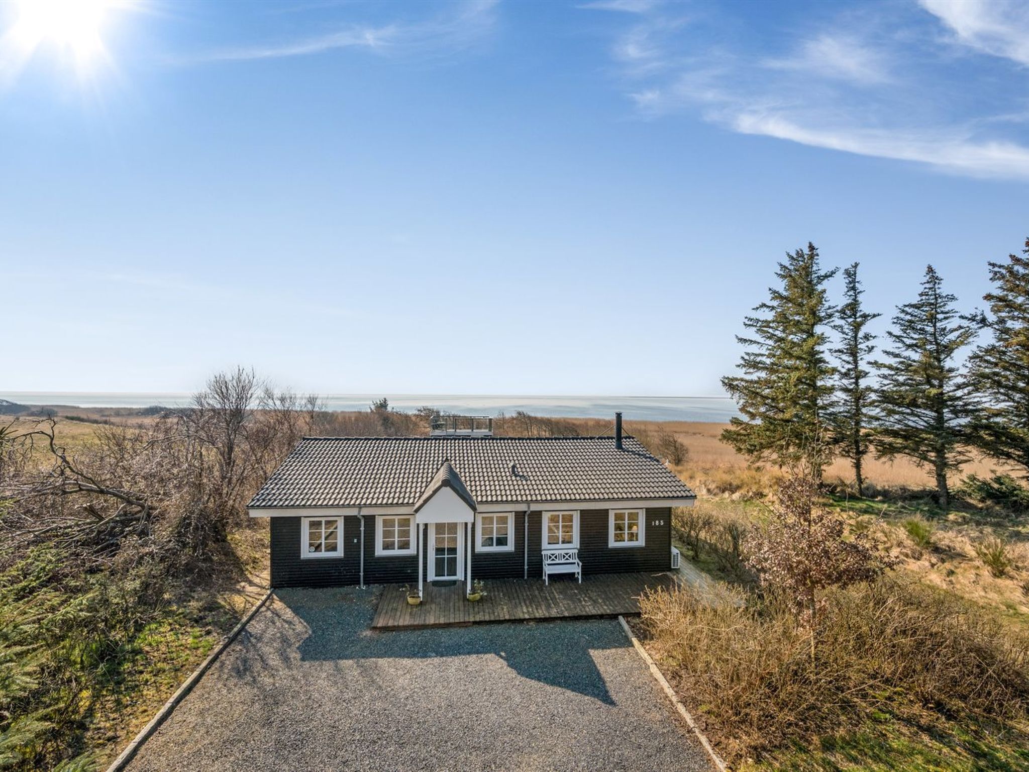 A house with a tiled roof, a porch, and a view of the ocean.