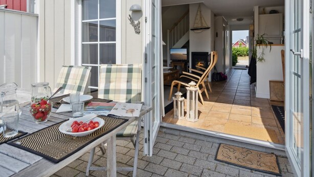 En åben patio med spisebord til to, et fjernsyn og en pejs.