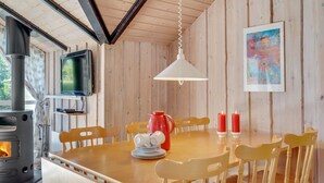 En inredning med träpanel, ett matbord, stolar, en öppen spis, en tv och ljus.