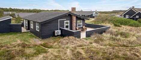 A modern house with a large deck, surrounded by natural landscape.