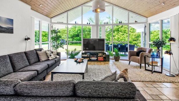 Un salon spacieux doté d’un grand téléviseur, de sièges confortables et offrant une vue sur l’extérieur.