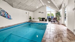 Une grande piscine intérieure avec un sol carrelé et un plafond haut.