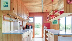 Un interno in legno con angolo cottura, caratterizzato da un lungo bancone, pensili e utensili appesi.