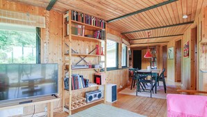 Interno di una baita in legno con TV, libreria e zona pranzo.