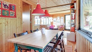 Un interno in legno con un tavolo da pranzo, sedie e lampade a sospensione.