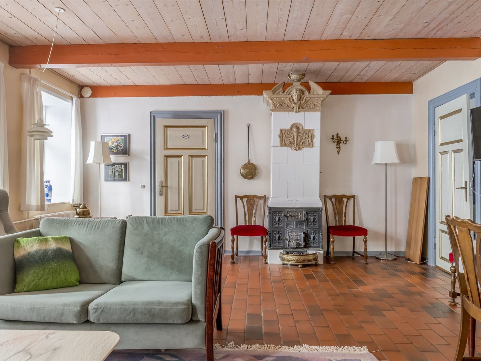 A living room with a sofa, chairs, a fireplace, and a door.