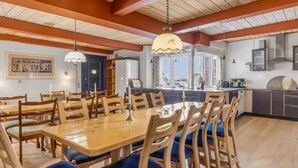 A dining area with a wooden table and chairs, a kitchen with modern appliances, and a view through large windows. - "Tilla" - 600m from the sea by Interhome (Bredebro)