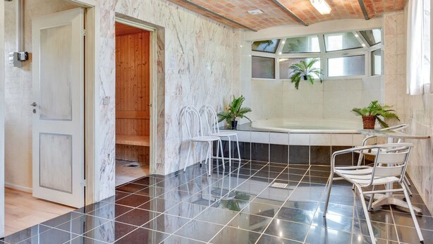 A modern bathroom with a black tiled floor, a white bathtub, and a wooden door. - "Tilla" - 600m from the sea by Interhome (Bredebro)