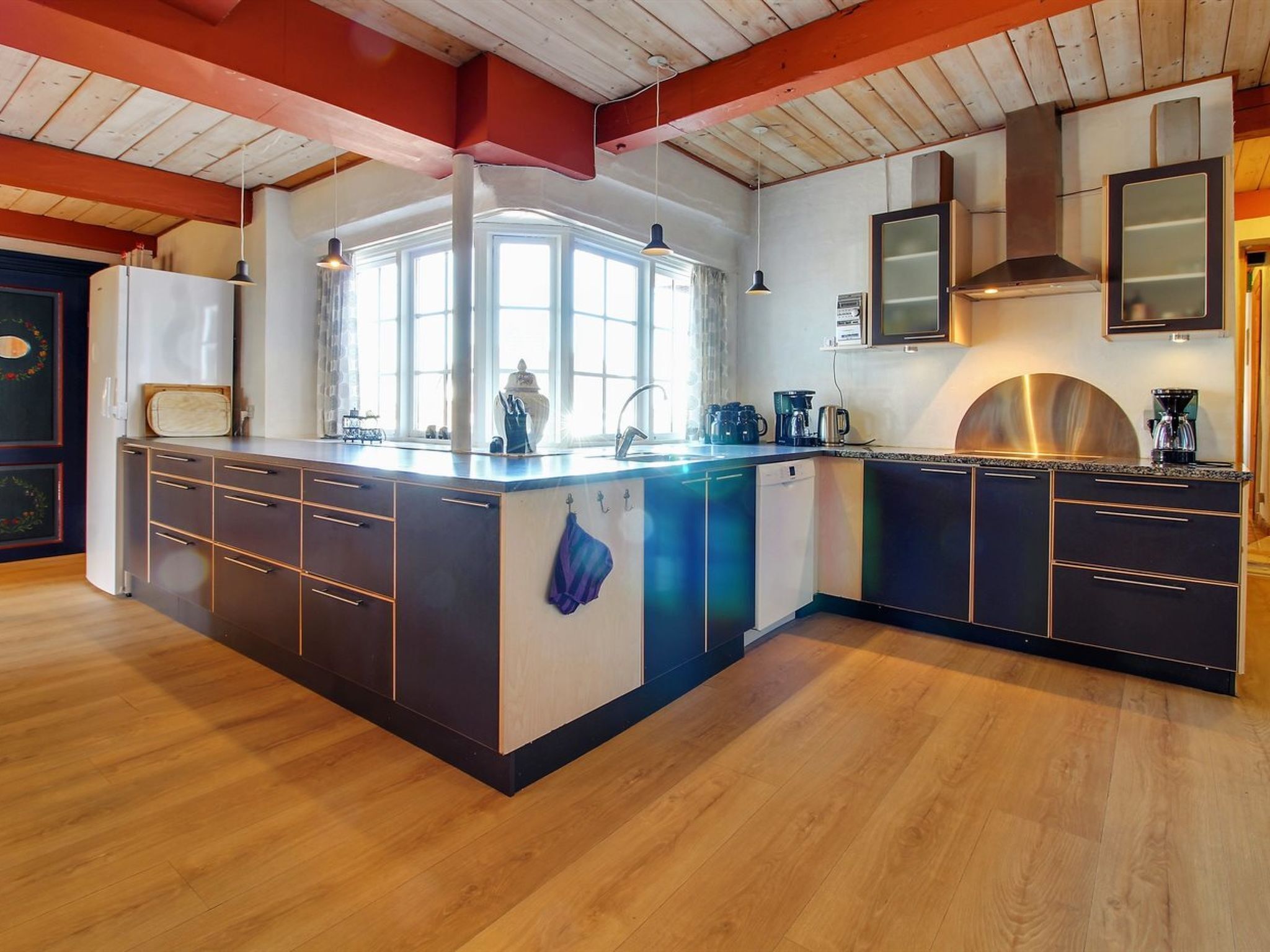 Uma cozinha moderna com ilha central, eletrodomésticos embutidos e uma grande janela que traz luz natural.