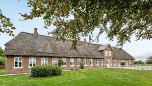 A large brick building with a thatched roof, surrounded by a well-maintained lawn and a hedge. - "Tilla" - 600m from the sea by Interhome (Bredebro)