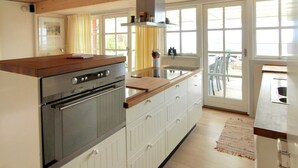 Een moderne keuken met een ingebouwde oven, een houten aanrechtblad en een groot raam dat voor natuurlijk licht zorgt.