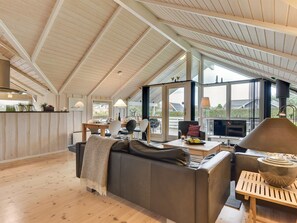 Een ruime loft met een hoge plafon, een gezellige zithoek met een bank en stoelen, een eettafel en een open haard.