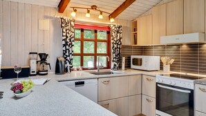 Une cuisine moderne avec des meubles en bois, un four à micro-ondes encastré, une cuisinière et une machine à café.
