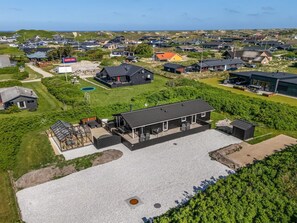 Et moderne boligområde med huse, en swimmingpool og en stor bygning med en overdækket terrasse.