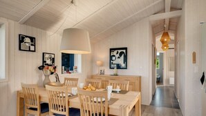 A dining area with wooden furniture, pendant lighting, and wall art.