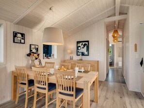 A dining area with a wooden table, chairs, and a hanging light fixture.