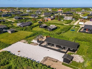 Una zona residencial con casas, un espacio abierto amplio y una masa de agua al fondo.