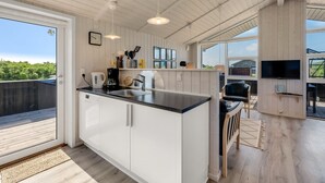 A modern kitchen with a large island, white cabinetry, and a dining area with a TV.