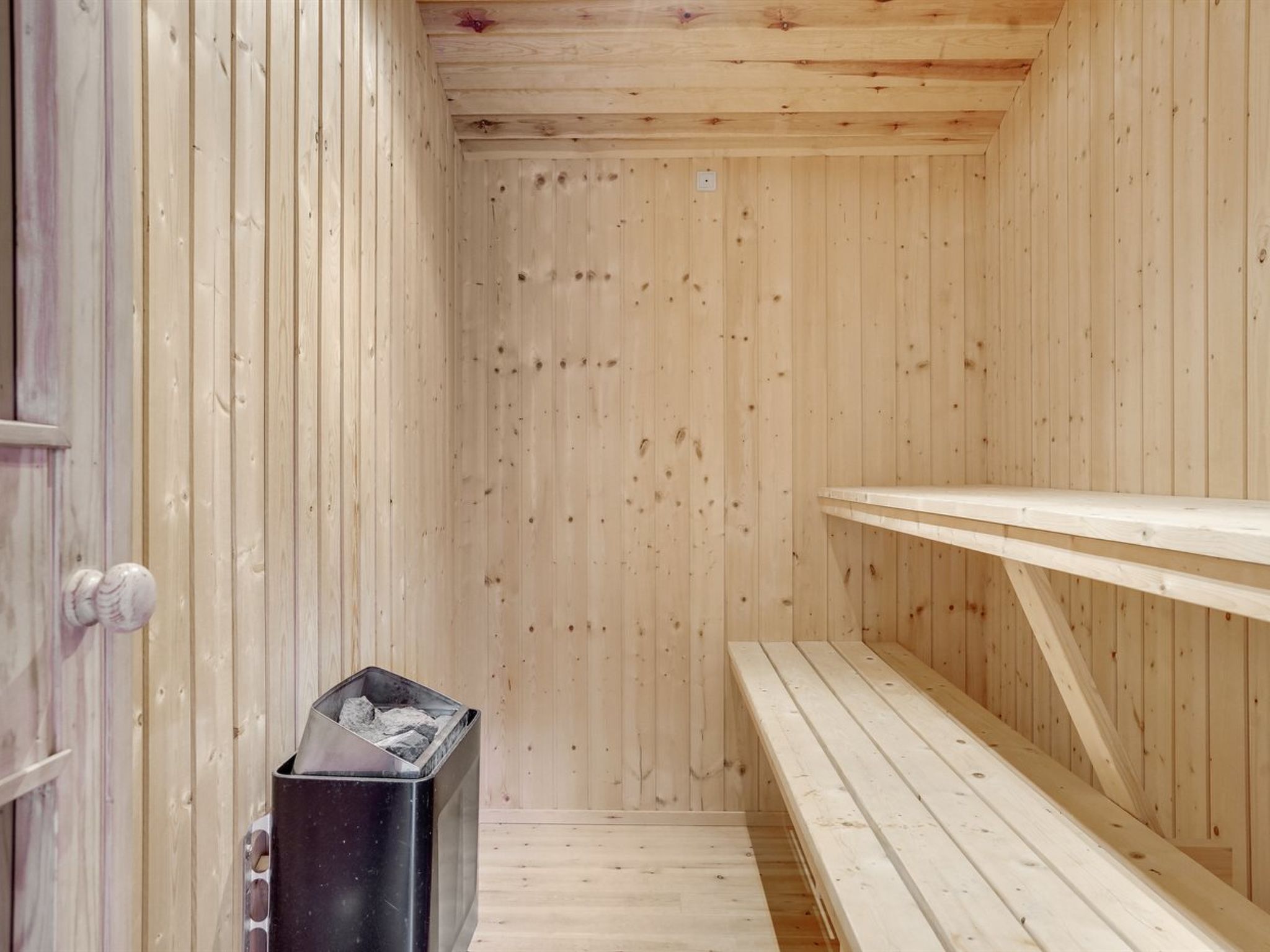 A wooden sauna with benches and a trash bin.