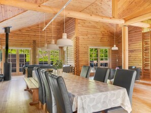 A log cabin interior with a dining area, wooden walls, and hanging pendant lights.