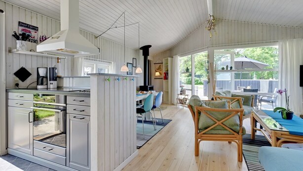 Een moderne keuken met witte kasten, een koffieapparaat en een eethoek met een tafel en stoelen.