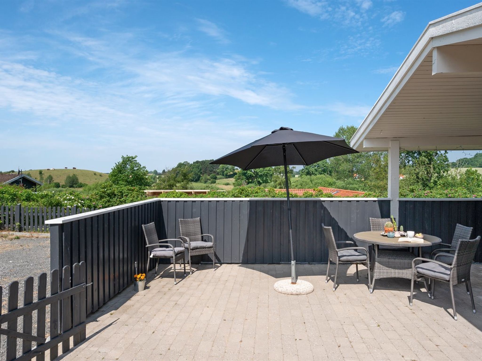 A patio with outdoor furniture, a table, and an umbrella.