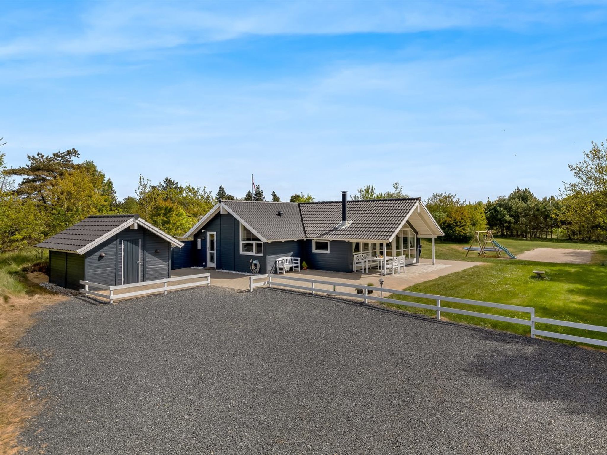 Een gebouw met twee verdiepingen, een overdekt terras en een speeltuin.
