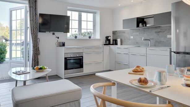 Una cucina moderna con mobili bianchi, forno integrato e un'ampia finestra.